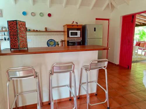 a kitchen with two stools at a counter with a refrigerator at Villa Les Bougainvilliers in Capesterre-de-Marie-Galante