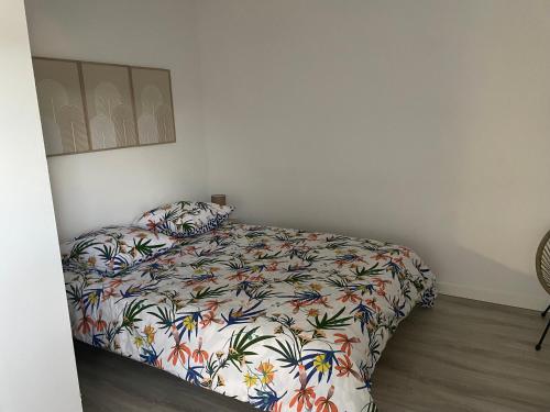 a bedroom with a bed with a floral bedspread at Maison en campagne sur terrain de 800 m2 in Saint-Germain-le-Guillaume