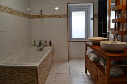 a bathroom with a tub and two sinks and a window at Maison 3 chambres , terrasse et garage à 20 min de La Rochelle in Nuaillé-dʼAunis