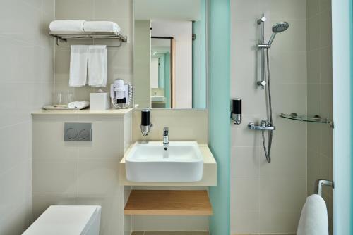 新加坡Holiday Inn Express Singapore Katong by IHG的带水槽和淋浴的白色浴室