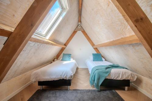 two beds in a small attic room with a window at Perfect Stay Holiday, Sea View in Egmond aan Zee