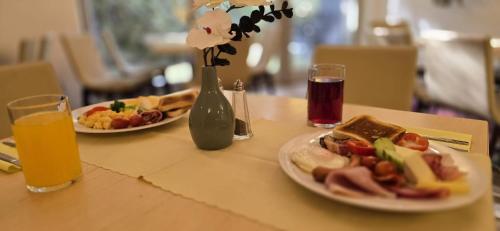a table with two plates of food and a vase with flowers at Anenský Apartmán C303 s wellness , O2 TV a stabilní rychlou WIFI, s možností dokoupení bufetových snídaní a s možností dokoupení masáží in Harrachov