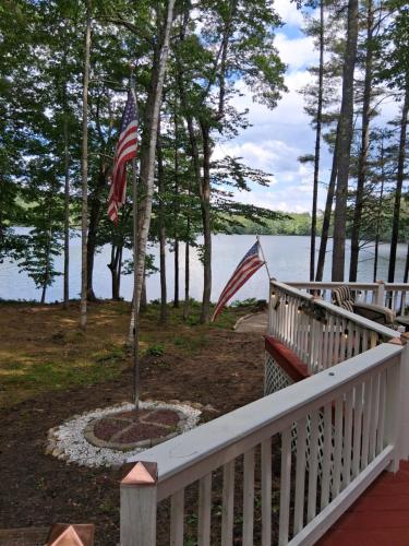 two american flags on a porch next to the water at Camp Parker Pond in Casco