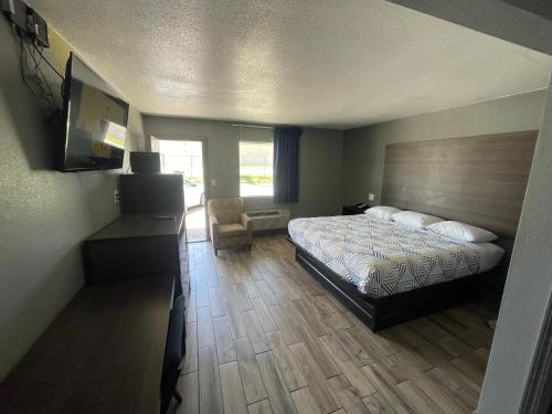 a bedroom with a bed and a desk and a chair at Gateway Motor Inn in Tulsa