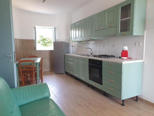 a kitchen with green cabinets and a stove top oven at Capomare2 in Capo Vaticano