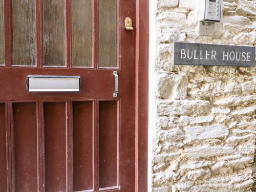 a red door with a sign next to a building at Smugglers Loft in Looe
