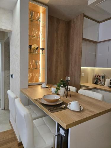 a kitchen with a wooden table and white chairs at In lux spa apartman 2 in Vrnjačka Banja