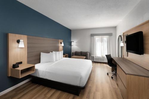 a hotel room with a bed and a television at Baymont by Wyndham Moss Point in Moss Point