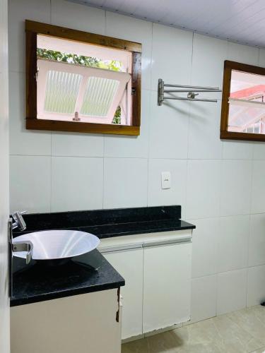 ein weißes Badezimmer mit Waschbecken und Fenster in der Unterkunft Cantinho Familia in Ouro Preto