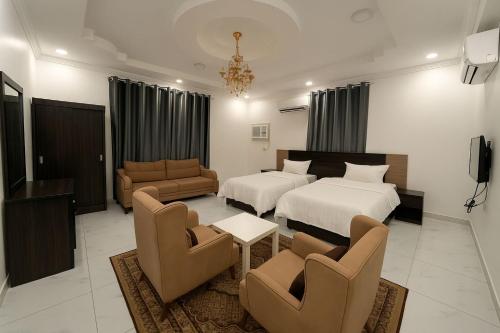 a hotel room with two beds and a living room at منازل الباحة للشقق الفندقية in Al ‘Āmirah