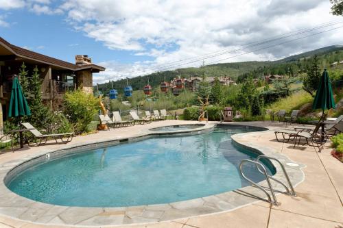a large swimming pool with chairs and a house at Shadowbrook 303 in Snowmass Village