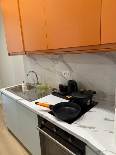a kitchen counter with a frying pan and a sink at Modern City Centre Apartment in Durrës