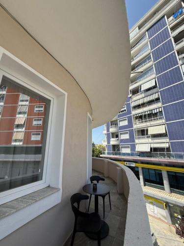 a balcony with two chairs and a table and a window at Modern City Centre Apartment in Durrës