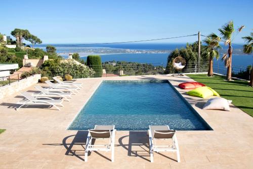 une piscine avec des chaises et l'océan en arrière-plan dans l'établissement Villa 5 BDs Breathtaking Views Large Pool Jacuzzi, à Carqueiranne