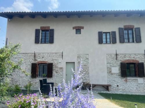 a building with black windows and purple flowers at Cascina Mabette in Farigliano