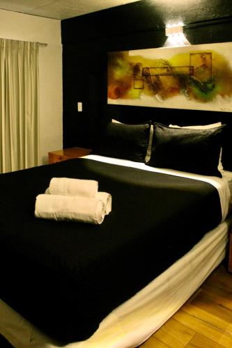 a bedroom with a black bed with towels on it at Grand Bellas artes in Santiago