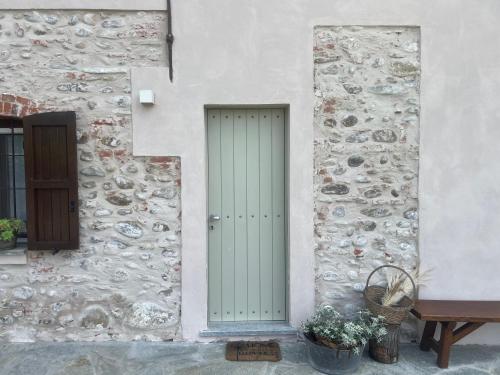 a stone building with a green door and a bench at Cascina Mabette in Farigliano