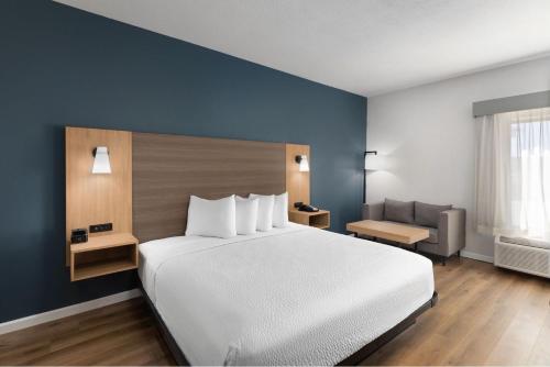a bedroom with a large white bed and a couch at Baymont by Wyndham Moss Point in Moss Point
