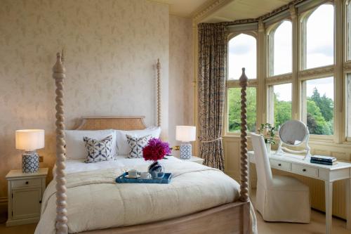 a bedroom with a bed and a desk and windows at Horsted Place Hotel in Uckfield