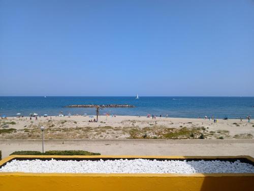 a beach with an umbrella and people on the beach at Front de mer - Le Barcarès in Le Barcarès