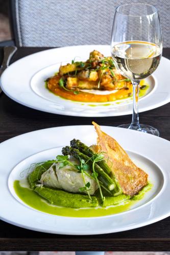 two plates of food on a table with a glass of wine at Horsted Place Hotel in Uckfield