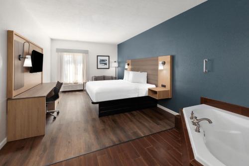 a hotel room with a bed and a bath tub at Baymont by Wyndham Moss Point in Moss Point