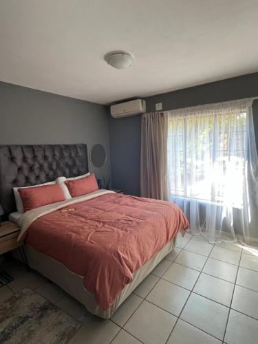 een slaapkamer met een bed met rode lakens en een raam bij 2 Spacious bedroom apartment in Lephalale