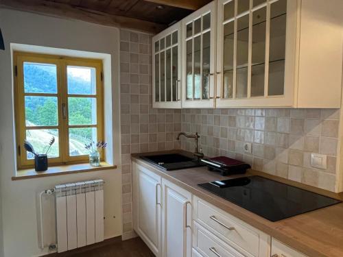 a kitchen with white cabinets and a sink and a window at Apartment Abinkar in Tolmin