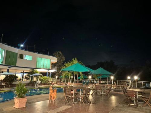 a patio with tables and umbrellas at night at Hotel Cascada Cristalina in Melgar