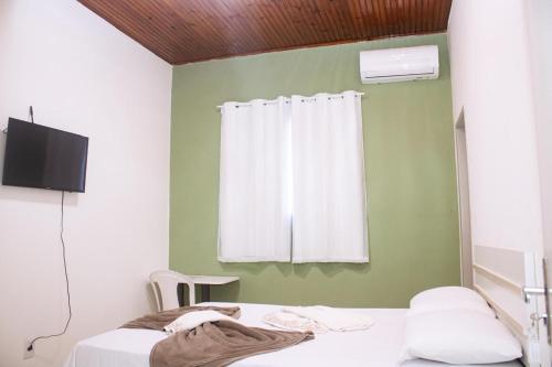 a room with two beds and a window with a curtain at Pousada Salomão in Teixeira de Freitas