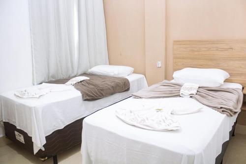 two beds in a room with white sheets at Pousada Salomão in Teixeira de Freitas