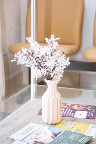 a white vase with flowers in it on a table at Pousada Salomão in Teixeira de Freitas