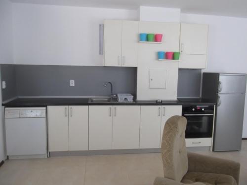 cocina con armarios blancos, fregadero y silla en Apartment Sredna Gora, en Burgas