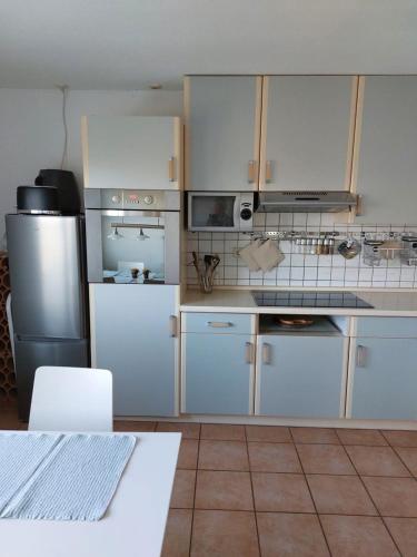 a kitchen with white cabinets and a stainless steel refrigerator at Ferienwohnung zum Flaaden in Neumünster