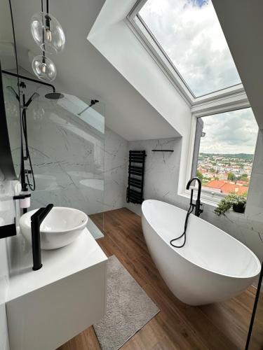une salle de bains avec une grande baignoire blanche et une fenêtre dans l'établissement Willa Matejki - Apartament 8a, à Przemyśl