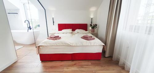 - une chambre avec un lit rouge et une baignoire dans l'établissement Willa Matejki - Apartament 8a, à Przemyśl