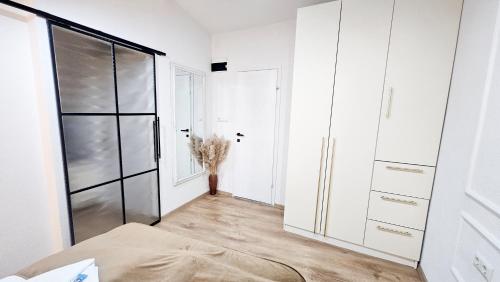 a bedroom with white walls and a glass closet at Apartments HAN 2 Sarajevo in Sarajevo