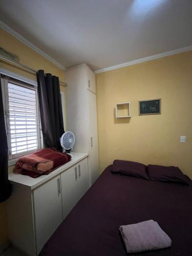 a bedroom with two beds and a window with a fan at Kasa Kaya in Araraquara