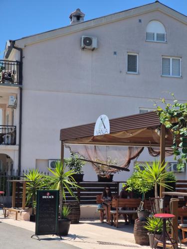 a person sitting on a bench under a wooden umbrella at Panorama view apartment VANJA in Baošići