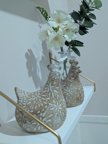 two vases sitting on a shelf with flowers in them at La Maison d'Arlette - Maison d'Hôte et Gite au coeur de l'Isère à 10 mn de Voiron, capitale de la Chartreuse, et du Lac de Paladru in Saint-Blaise-du-Buis