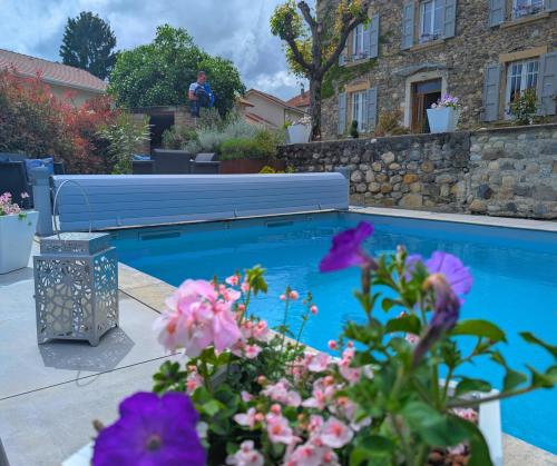 a swimming pool in a yard with flowers at La Maison d'Arlette - Maison d'Hôte et Gite au coeur de l'Isère à 10 mn de Voiron, capitale de la Chartreuse, et du Lac de Paladru in Saint-Blaise-du-Buis