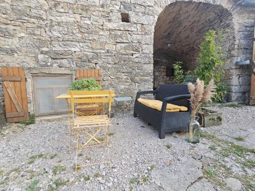 a patio with a couch and a table and chairs at Charmante maison caussenarde in Saint-Georges-de-Lévéjac