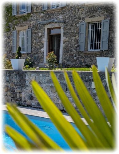 a house with a stone wall and a swimming pool at La Maison d'Arlette - Maison d'Hôte et Gite au coeur de l'Isère à 10 mn de Voiron, capitale de la Chartreuse, et du Lac de Paladru in Saint-Blaise-du-Buis