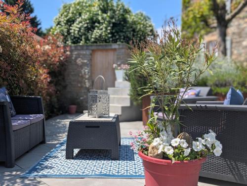a garden with a patio with plants and a table at La Maison d'Arlette - Maison d'Hôte et Gite au coeur de l'Isère à 10 mn de Voiron, capitale de la Chartreuse, et du Lac de Paladru in Saint-Blaise-du-Buis