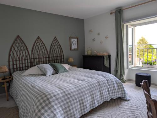 a bedroom with a bed with a checkered blanket and a window at La Maison d'Arlette - Maison d'Hôte et Gite au coeur de l'Isère à 10 mn de Voiron, capitale de la Chartreuse, et du Lac de Paladru in Saint-Blaise-du-Buis