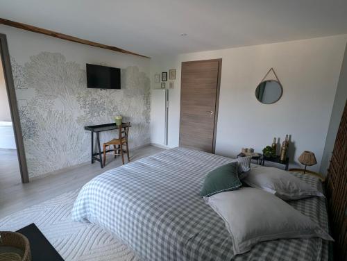 a bedroom with a bed and a table with a television at La Maison d'Arlette - Maison d'Hôte et Gite au coeur de l'Isère à 10 mn de Voiron, capitale de la Chartreuse, et du Lac de Paladru in Saint-Blaise-du-Buis