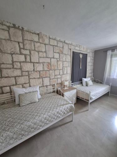 a bedroom with two beds and a stone wall at Apartment Lila garden in Bol