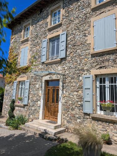 a stone house with blue shutters and a door at La Maison d'Arlette - Maison d'Hôte et Gite au coeur de l'Isère à 10 mn de Voiron, capitale de la Chartreuse, et du Lac de Paladru in Saint-Blaise-du-Buis