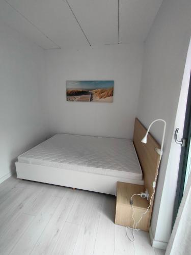a white bed in a room with a box at Apartamenty Słonecznikowa in Tupadły