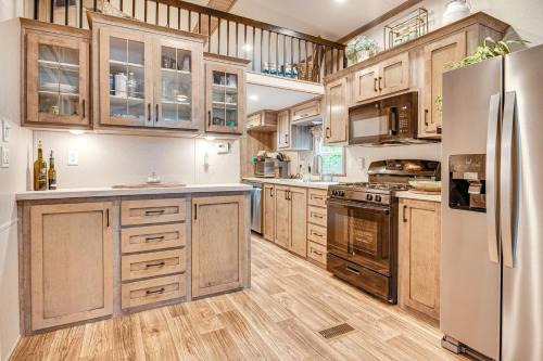 a kitchen with wooden cabinets and a stainless steel refrigerator at Walk to Lake Beaches Cabin with Patio in Belmont! in Belmont
